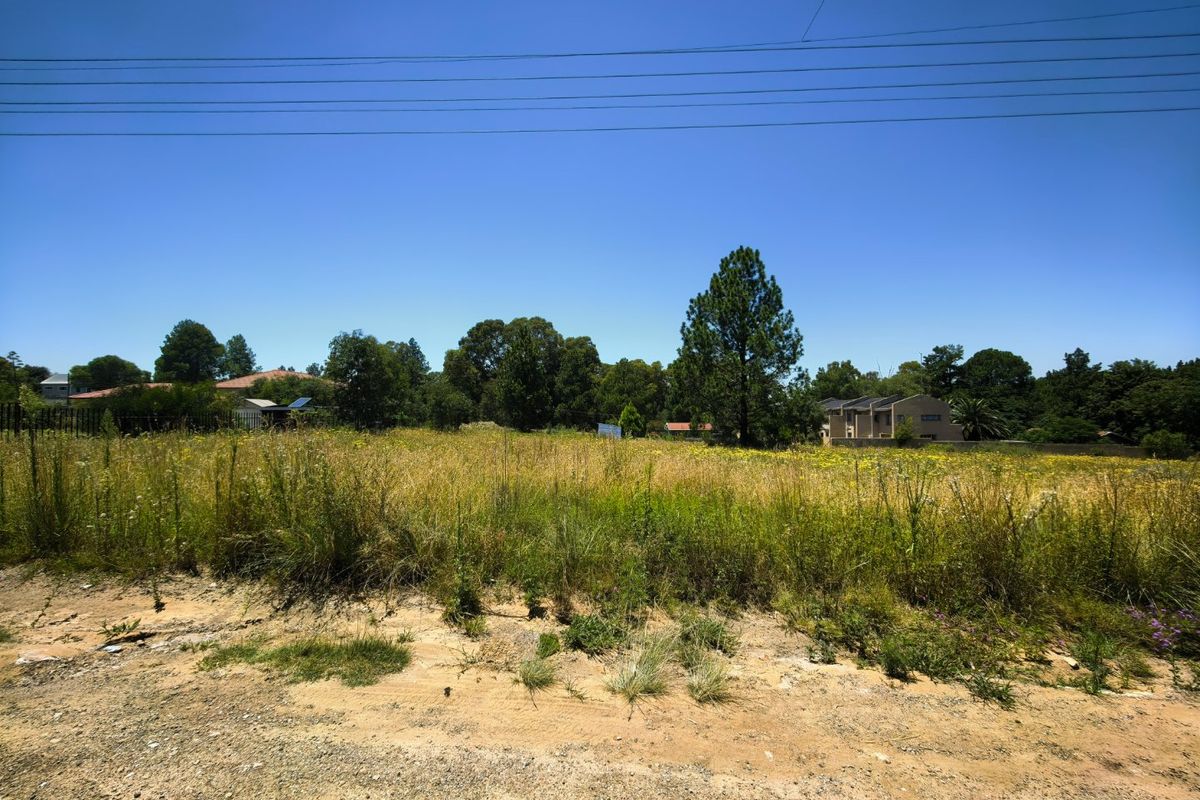 A large, undeveloped plot of land featuring overgrown grass and natural vegetation, offering potential for future residential development.