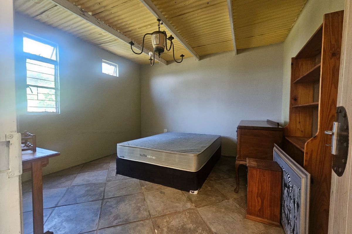A bedroom featuring tiled flooring and an exposed corrugated ceiling, providing a basic foundation for renovation and modernization.