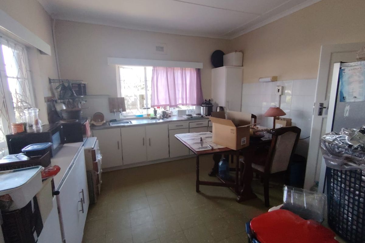 A functional kitchen featuring built-in cabinetry, a stainless steel sink, and tiled splashbacks, offering potential for modernization and renovation.