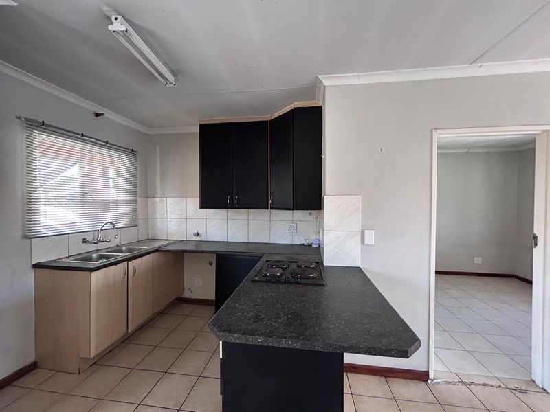 A functional kitchen featuring dark upper cabinets, light lower cabinetry, laminate countertops, a built-in hob, and tiled flooring throughout.