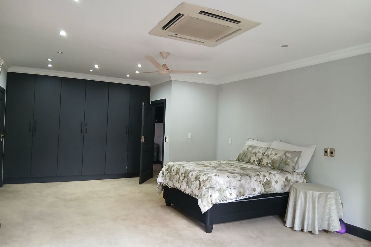 Spacious bedroom featuring extensive dark built-in cabinetry, recessed lighting, a ceiling fan, and integrated ducted air conditioning.