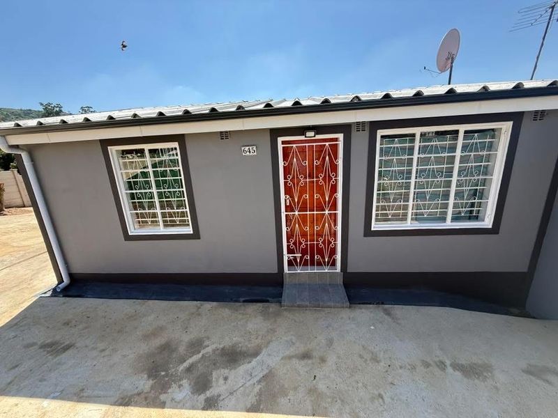 Front facade of a single-story house featuring a painted exterior, security gates on windows and door, and a concrete driveway.