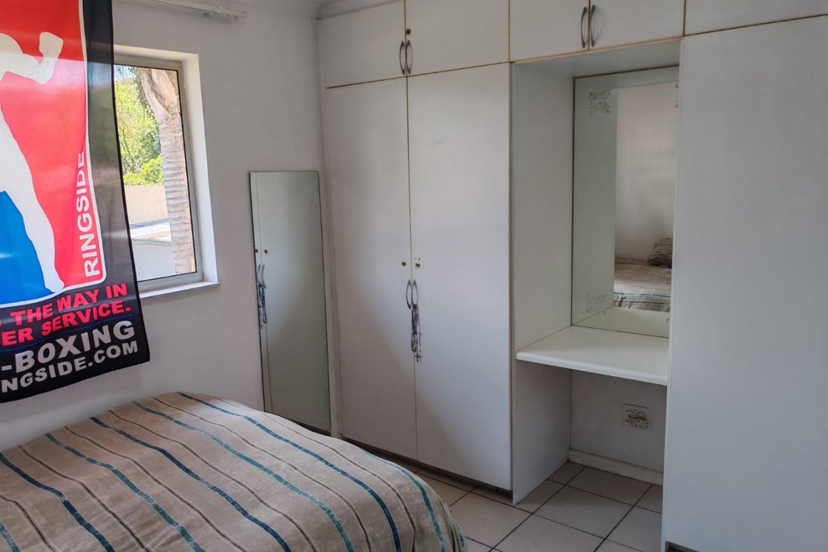 Bedroom featuring built-in white cabinetry with integrated vanity mirror and tiled flooring.