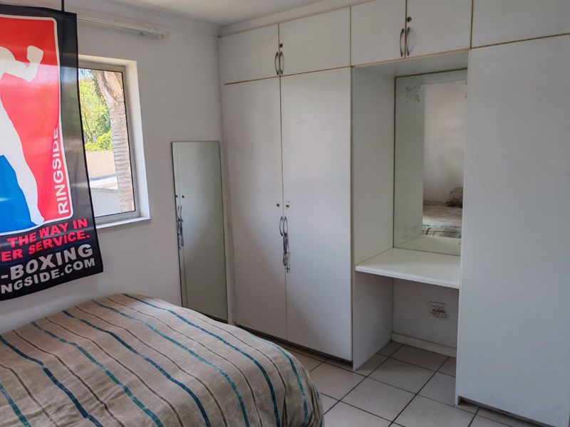 Bedroom featuring built-in white cabinetry with integrated vanity mirror and tiled flooring.