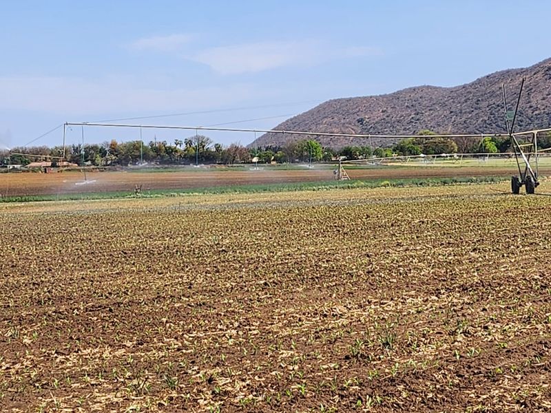 Expansive agricultural farmland featuring a large-scale center pivot irrigation system in operation across the cultivated fields.