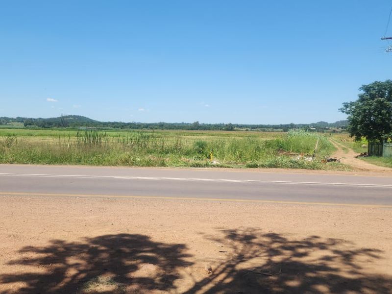 A view of the farm property from the adjacent road, showcasing the expansive landscape, natural terrain, and surrounding rural environment.
