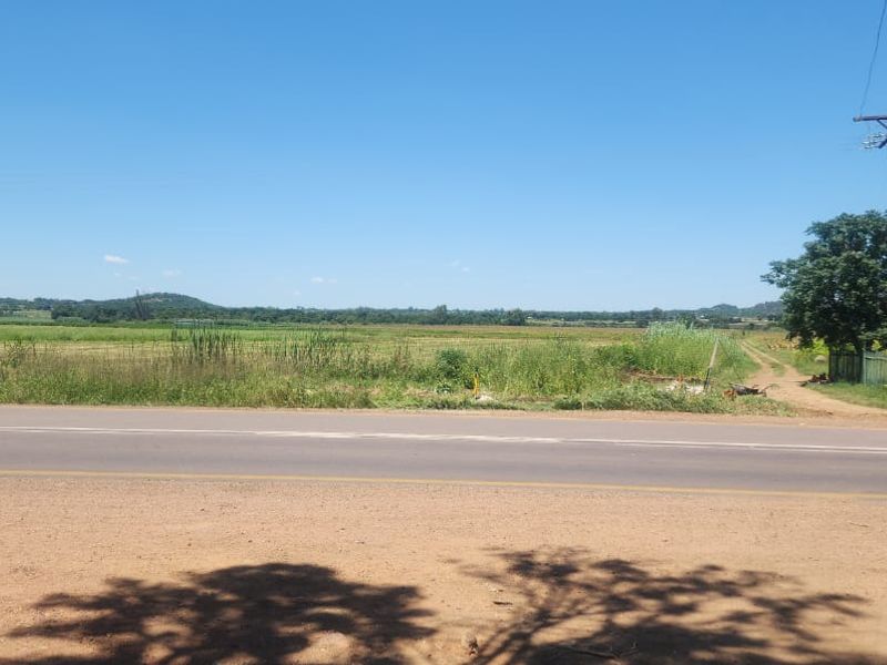 A wide-angle view of the farm property, showcasing the expansive landscape, surrounding hills, and direct access from the adjacent road.