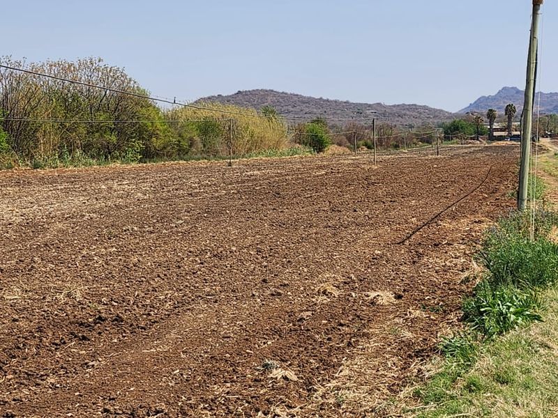 A view of a tilled agricultural field on the farm, featuring perimeter fencing and distant mountain views.