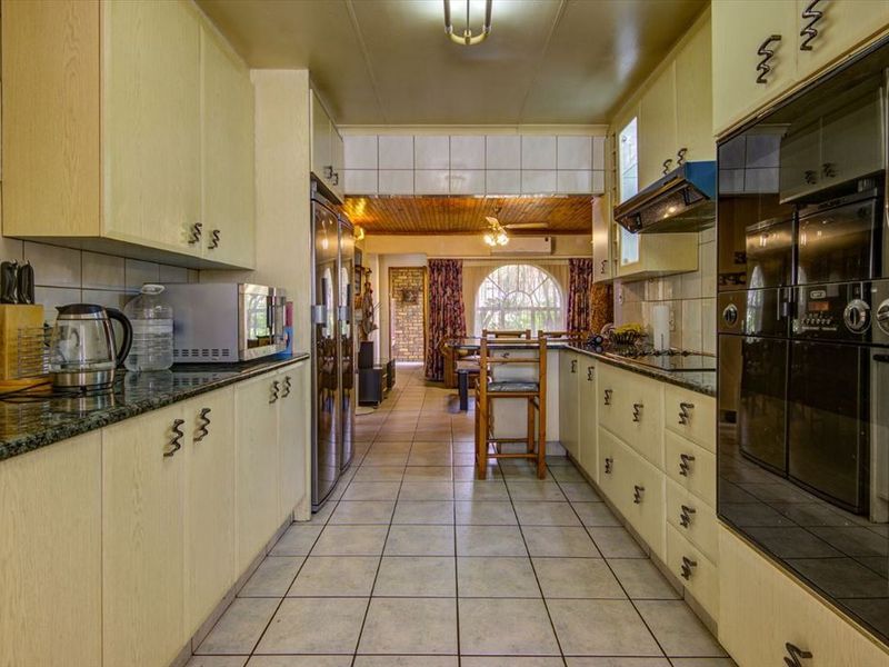 A functional galley-style kitchen featuring laminate cabinetry, granite countertops, and a built-in double oven, leading through to an adjacent living area.