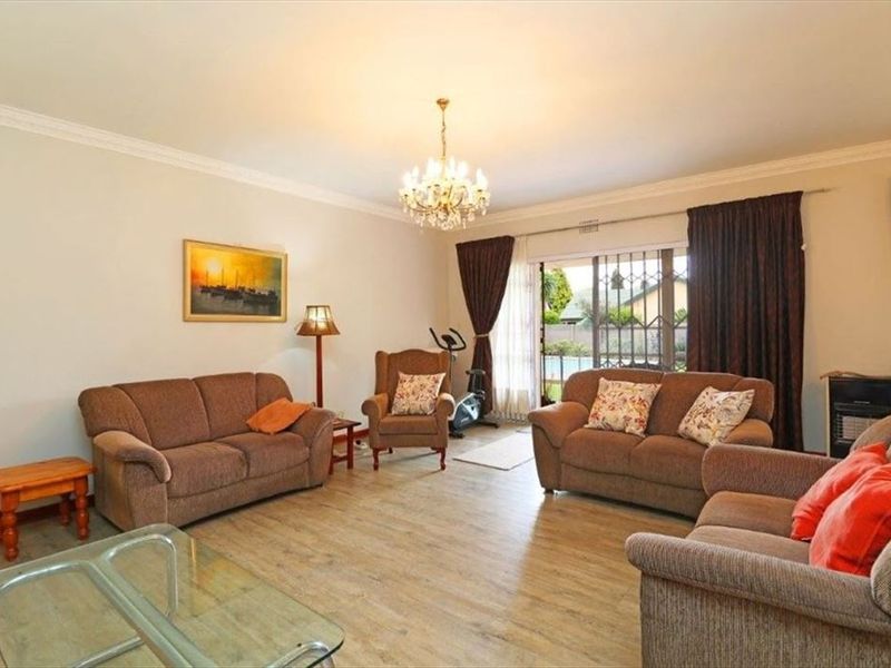 Spacious living room featuring laminate flooring, decorative cornice, and a sliding glass door providing access to the outdoor area.