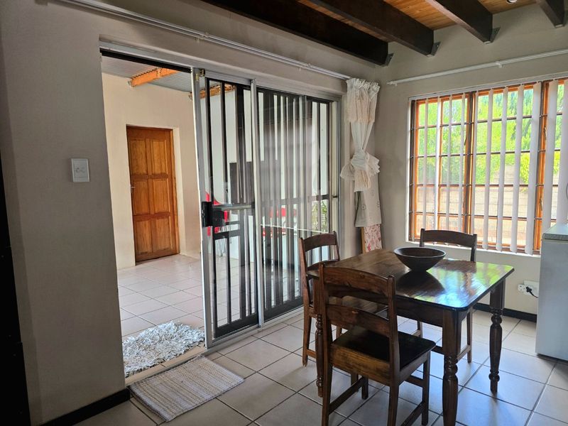 Dining area featuring exposed timber ceiling beams, tiled flooring, and a sliding glass door providing access to an adjacent covered patio space.