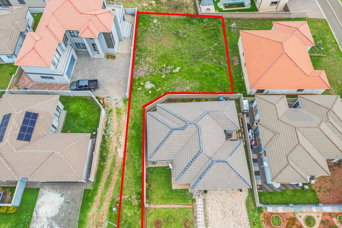 An aerial view of a vacant residential plot situated between established homes in a suburban estate.