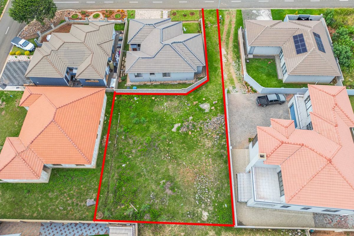 An aerial view of a vacant residential plot situated within a developed suburban estate, showing clear boundaries and surrounding properties.