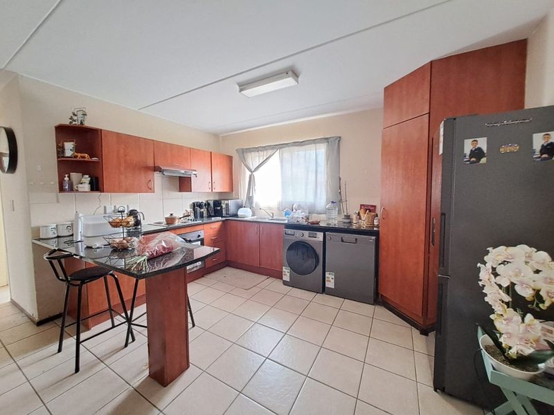 A functional kitchen featuring wooden cabinetry, granite countertops, a breakfast nook, and tiled flooring with integrated appliance spaces.