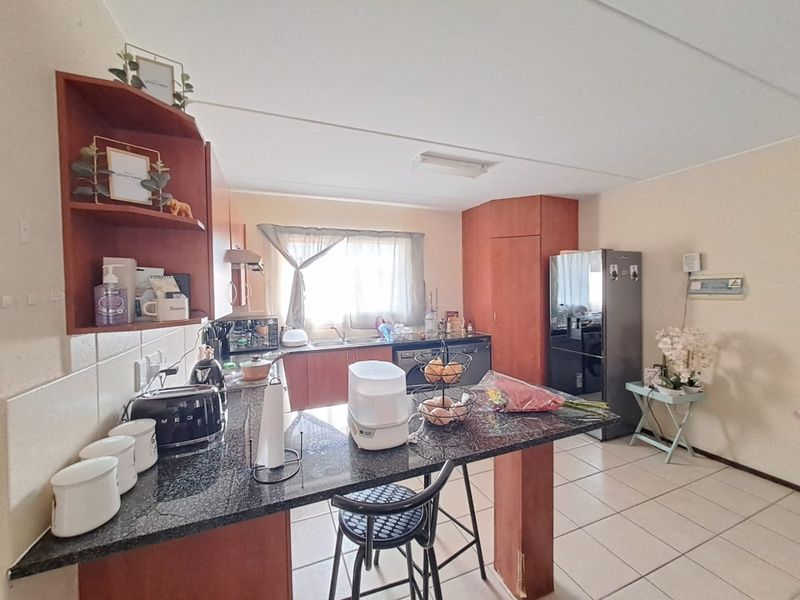 A functional kitchen featuring granite countertops, laminate cabinetry, and ceramic floor tiles, offering a practical layout with ample storage space.