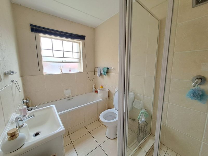 A functional bathroom featuring a bathtub, separate shower enclosure, toilet, and pedestal basin with neutral wall and floor tiling.