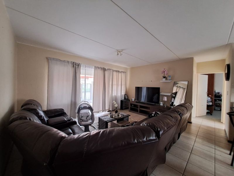 A functional living room featuring tiled flooring and a sliding glass door providing access to the exterior.