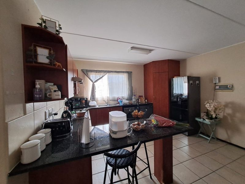 A functional kitchen featuring granite countertops, ample built-in cabinetry, and tiled flooring, offering a practical layout for daily meal preparation.