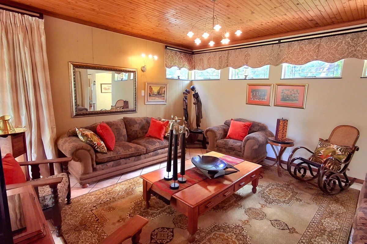 A cozy living room featuring a warm timber-paneled ceiling, clerestory windows for natural light, and neutral tiled flooring.