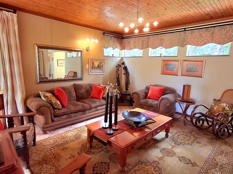 A cozy living room featuring a warm timber-paneled ceiling, clerestory windows for natural light, and neutral tiled flooring.