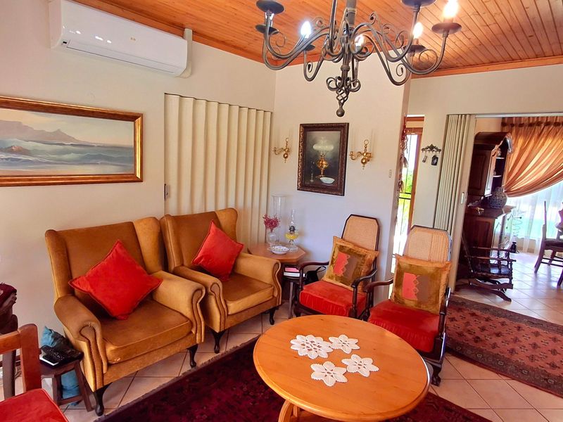 A cozy living room featuring a timber ceiling, tiled flooring, and a split-system air conditioner, with an open-plan flow into the adjacent dining area.