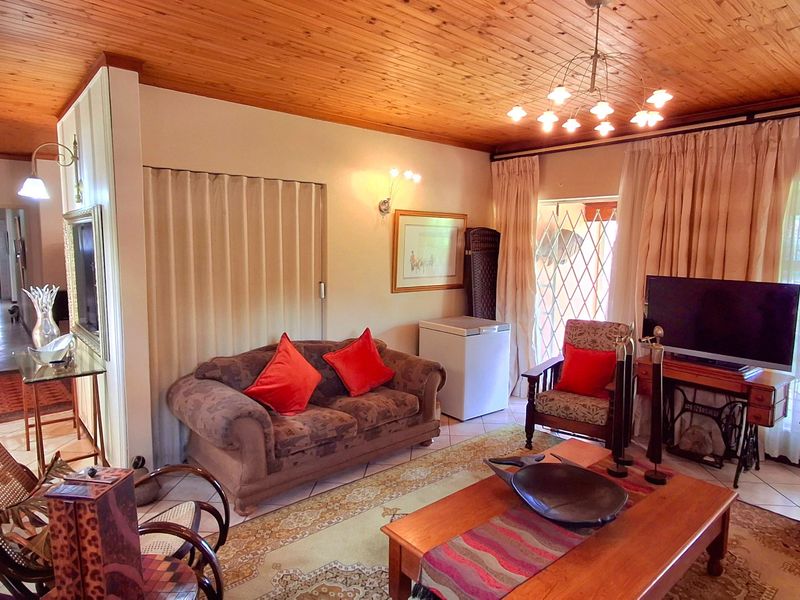 A living room featuring a timber tongue and groove ceiling, ceramic tiled flooring, and access to an outdoor area via a sliding security gate.