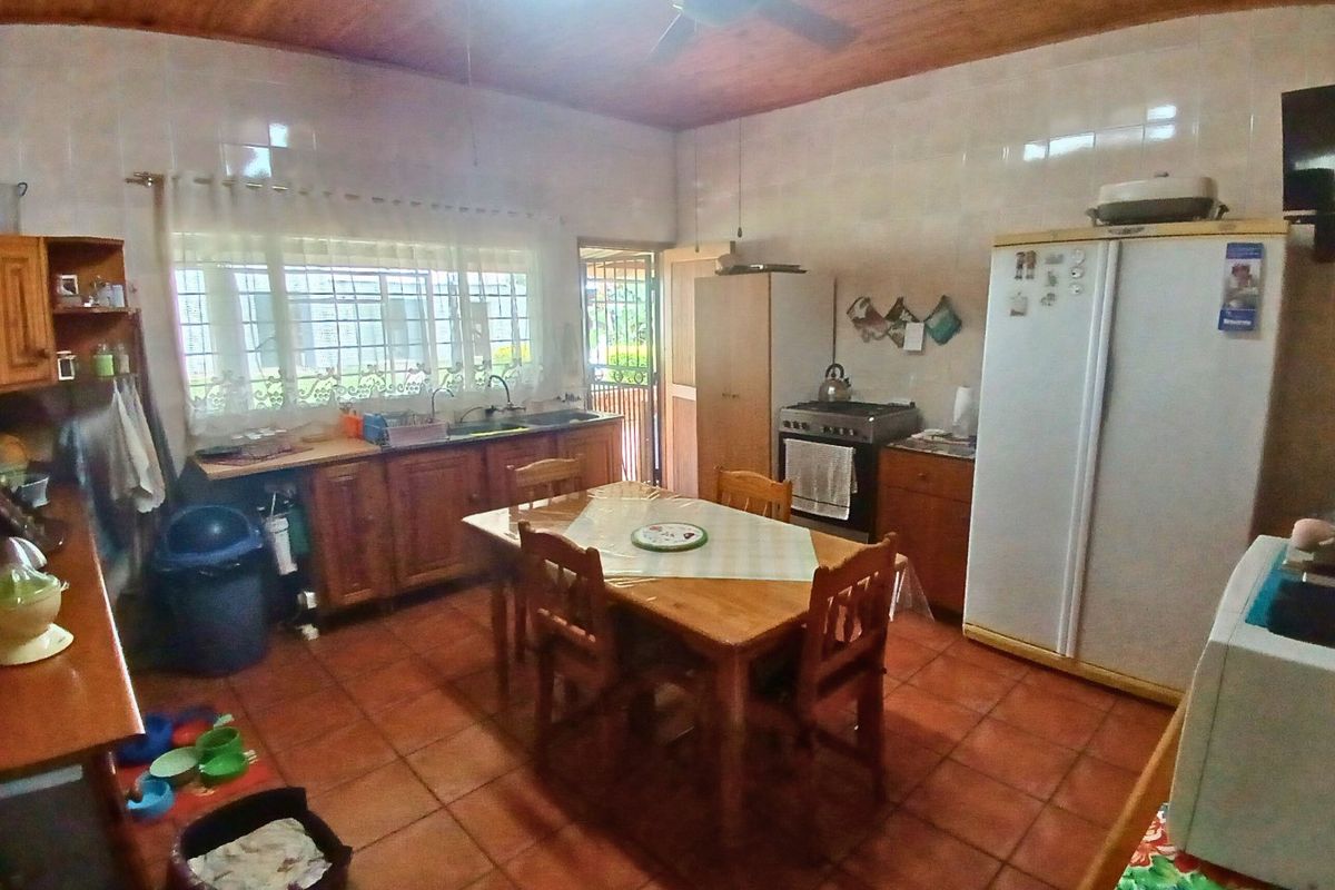 A functional kitchen featuring wooden cabinetry, a gas stove, double basin sink, and tiled flooring with a timber ceiling finish.