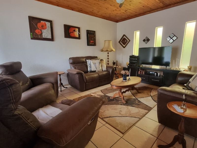 A comfortable living room featuring a warm timber ceiling, tiled flooring, and unique vertical slit windows that provide natural light.