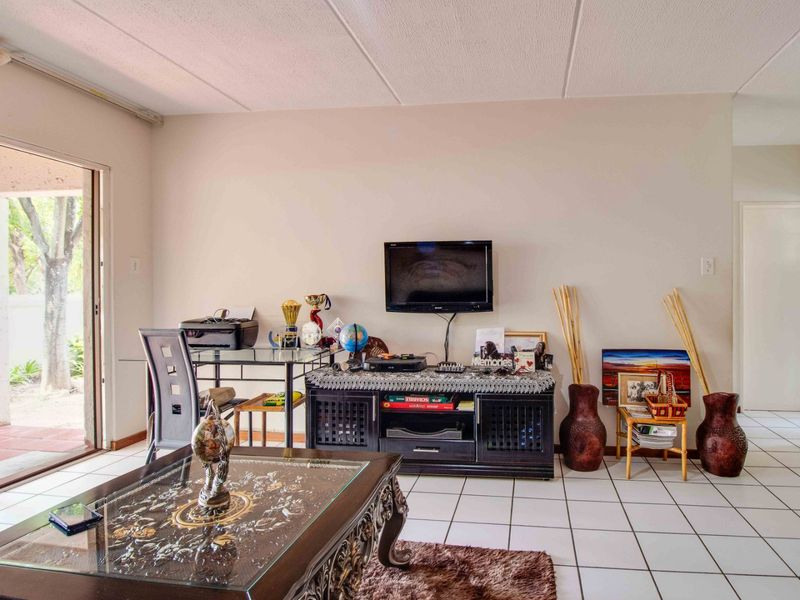 A living room featuring white tiled flooring and a sliding glass door providing access to an outdoor area.