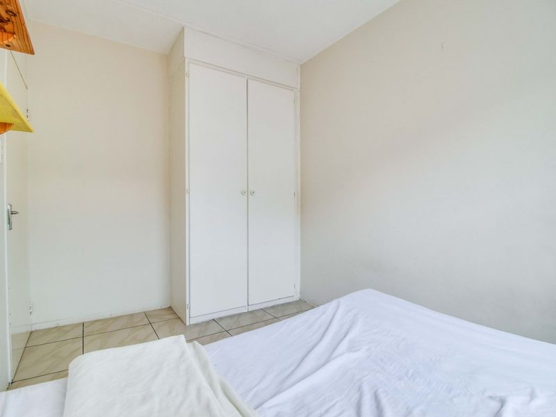 A functional bedroom featuring tiled flooring and a built-in wardrobe, offering a neutral space ready for personalization.