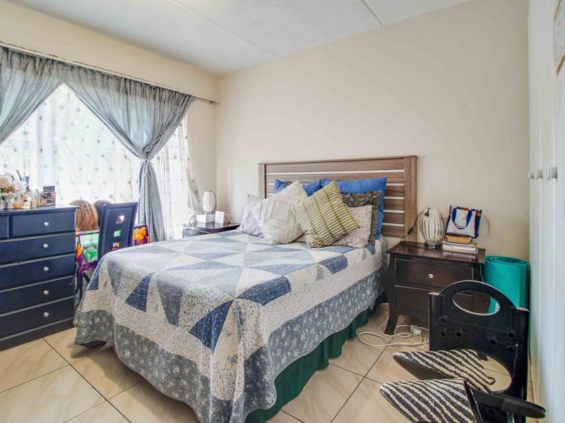 A functional bedroom featuring tiled flooring and built-in cupboard storage, offering a comfortable and practical living space.
