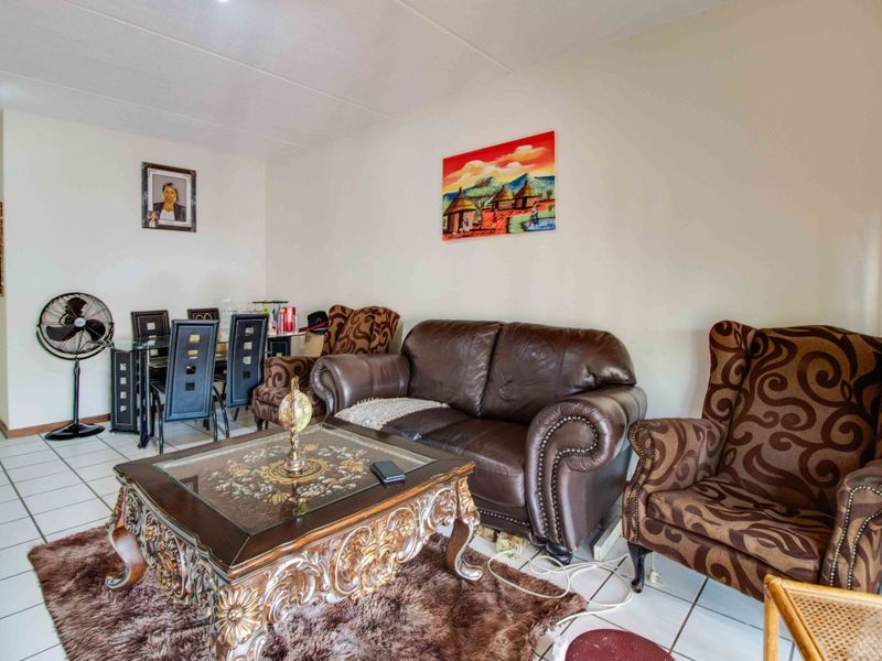A living room area featuring tiled flooring and neutral wall finishes, providing a functional space for relaxation and dining.