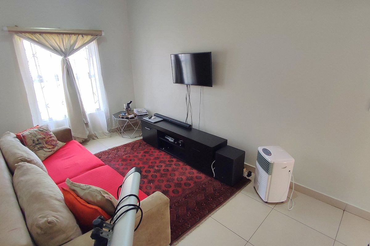 A living room featuring tiled flooring and a window with a curtain rod, providing a functional and neutral space.