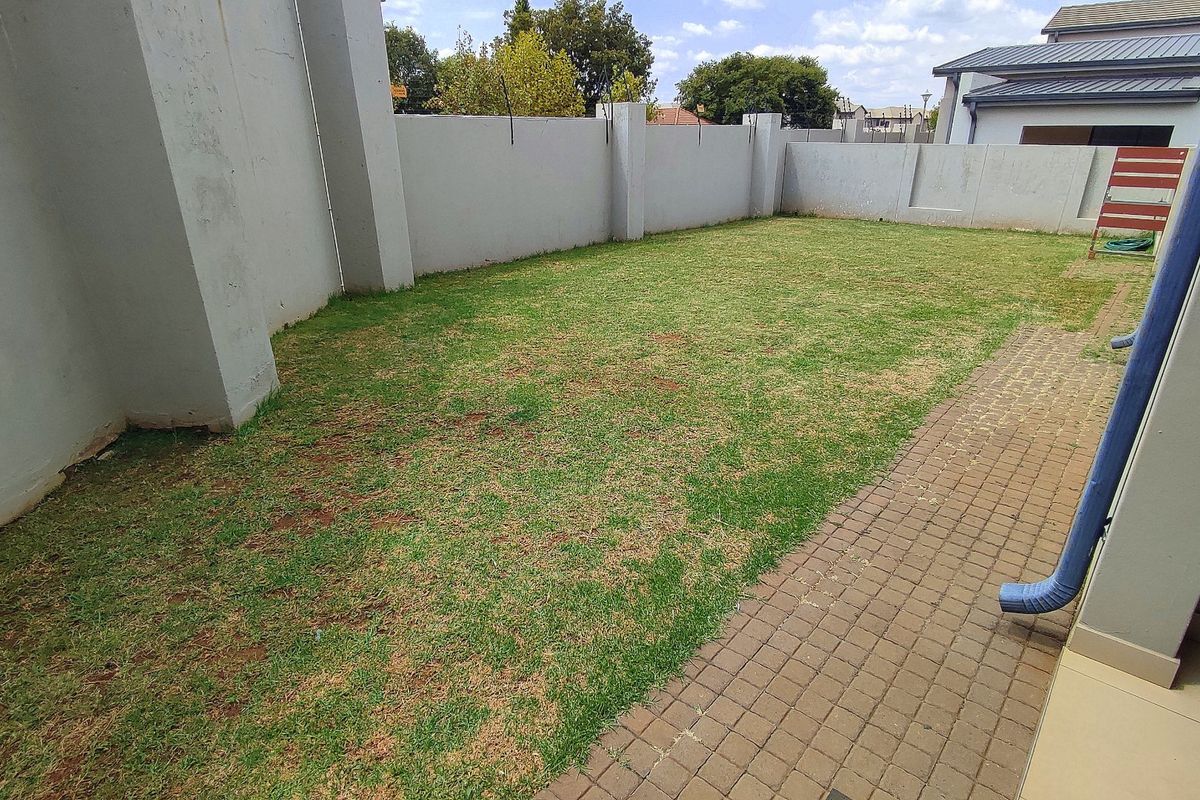 A private rear garden featuring a paved walkway and a perimeter wall, offering a blank canvas for landscaping and outdoor living improvements.