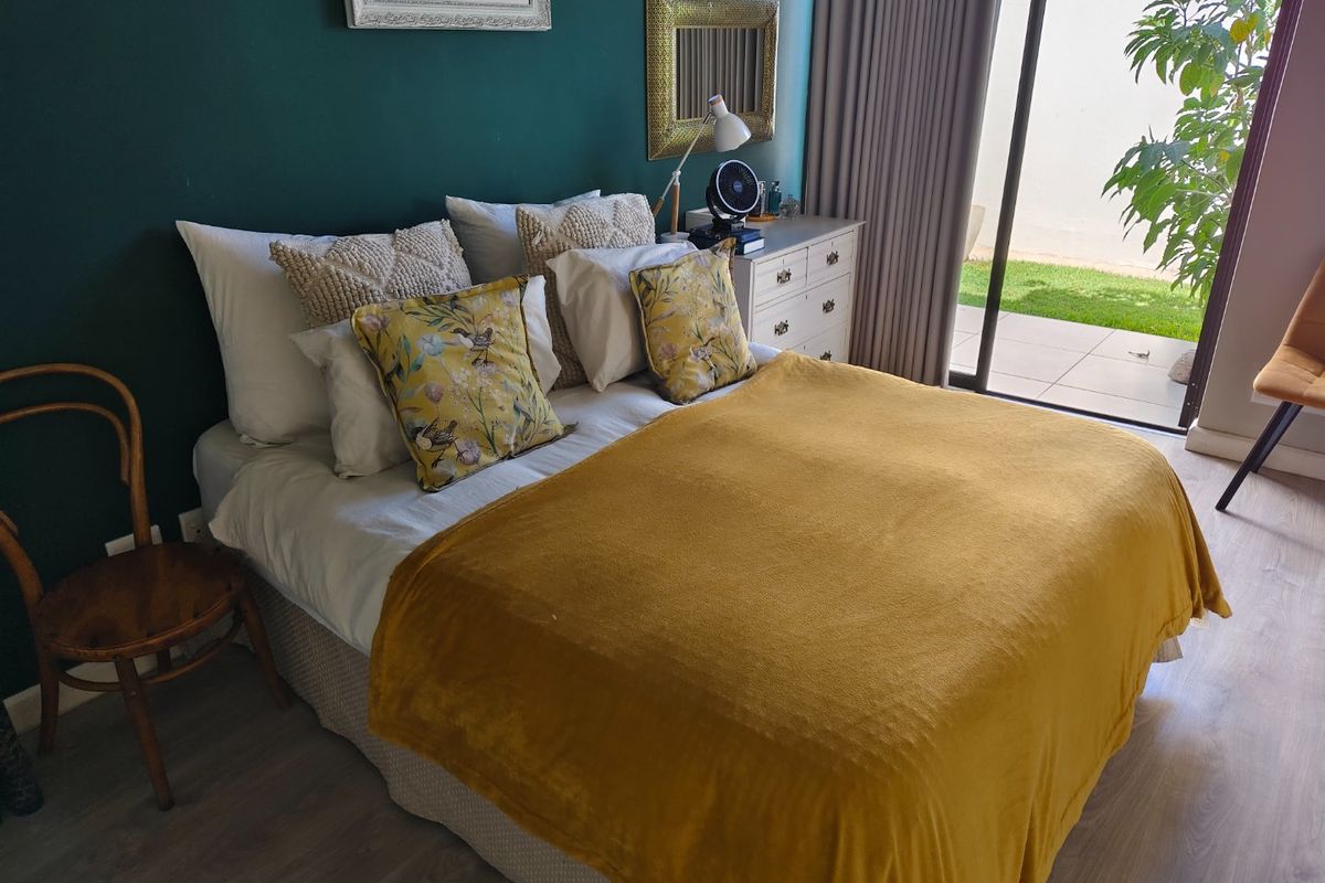 A well-maintained bedroom featuring laminate flooring and a large sliding glass door providing direct access to an outdoor patio area.