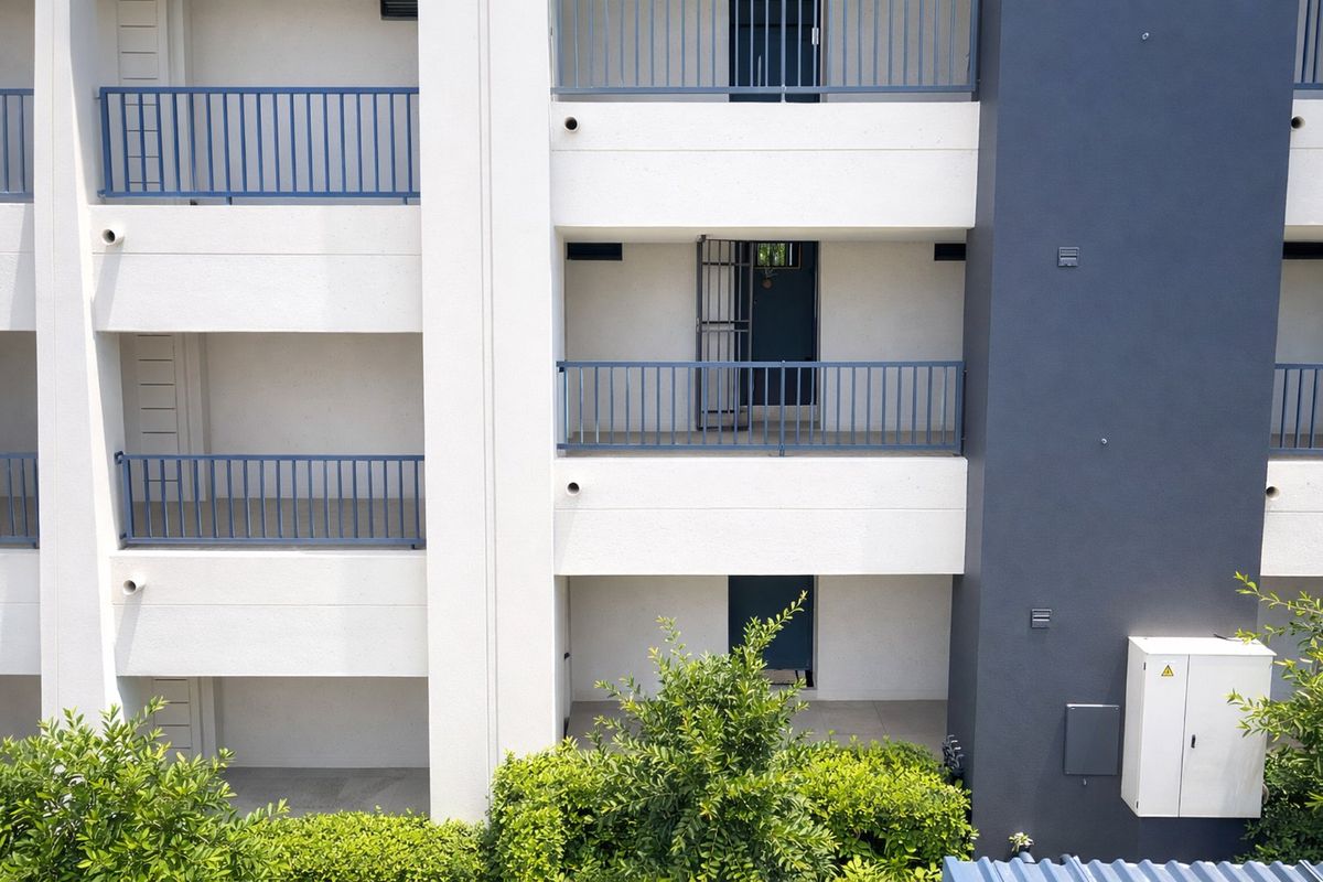 A view of the apartment building exterior featuring multiple levels with balconies, security gates, and clean modern finishes.