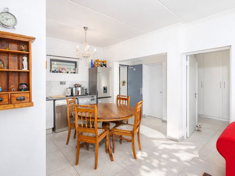 Open plan kitchen and dining area featuring tiled flooring, neutral walls, and built-in cabinetry, leading to a hallway with built-in storage cupboards.