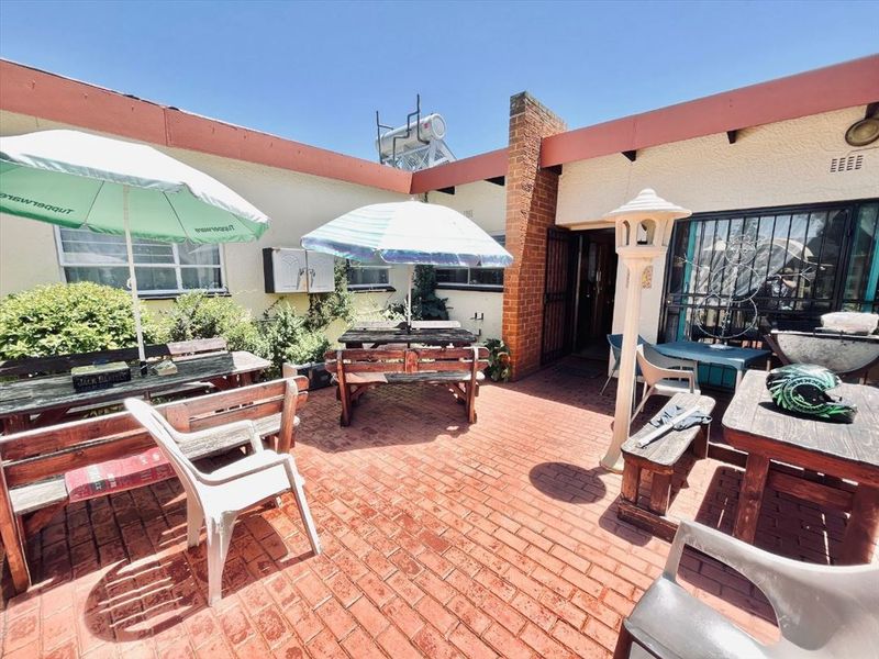 A paved outdoor patio area featuring a brick chimney and secure access points, providing a functional space for outdoor entertainment.