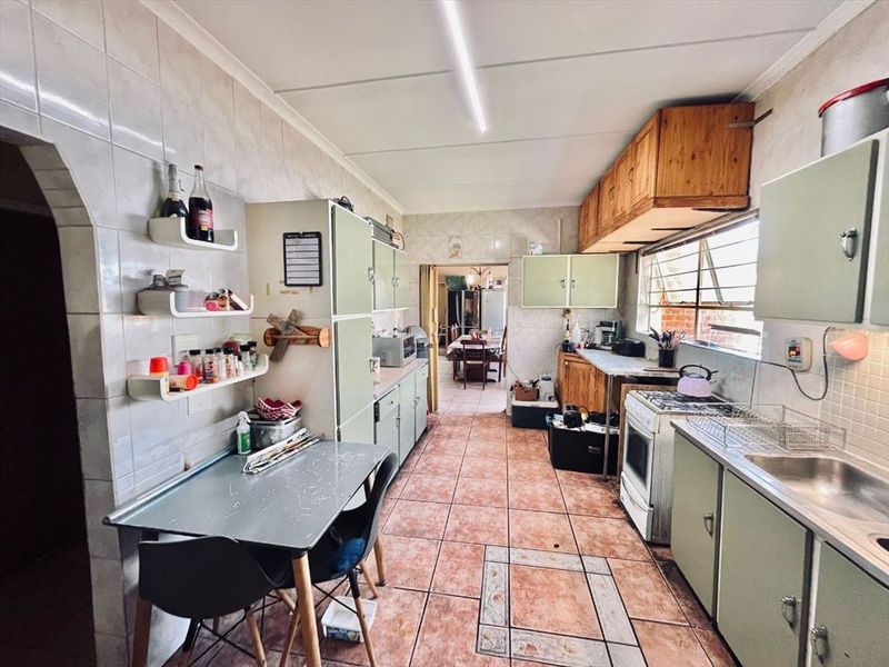 A dated kitchen featuring tiled walls and flooring, built-in cabinetry, and a freestanding stove, offering significant potential for modernization and renovation.