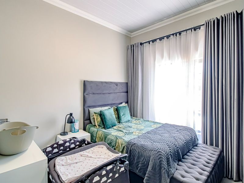 A well-maintained bedroom featuring crown molding and a tongue and groove ceiling, with large windows dressed in floor-to-ceiling curtains.