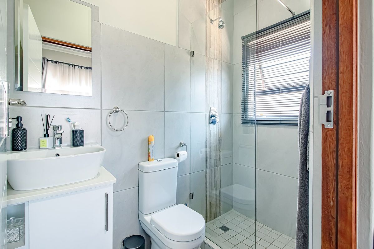 Modern bathroom featuring a vessel sink with vanity, a glass-enclosed shower, and neutral wall tiling.