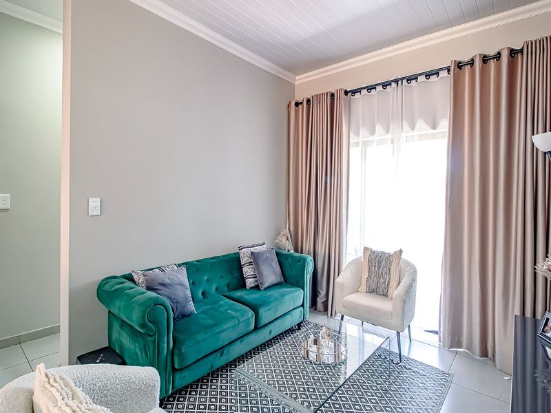 A bright living room featuring tiled floors, a tongue and groove ceiling, and a large sliding glass door providing access to the exterior.
