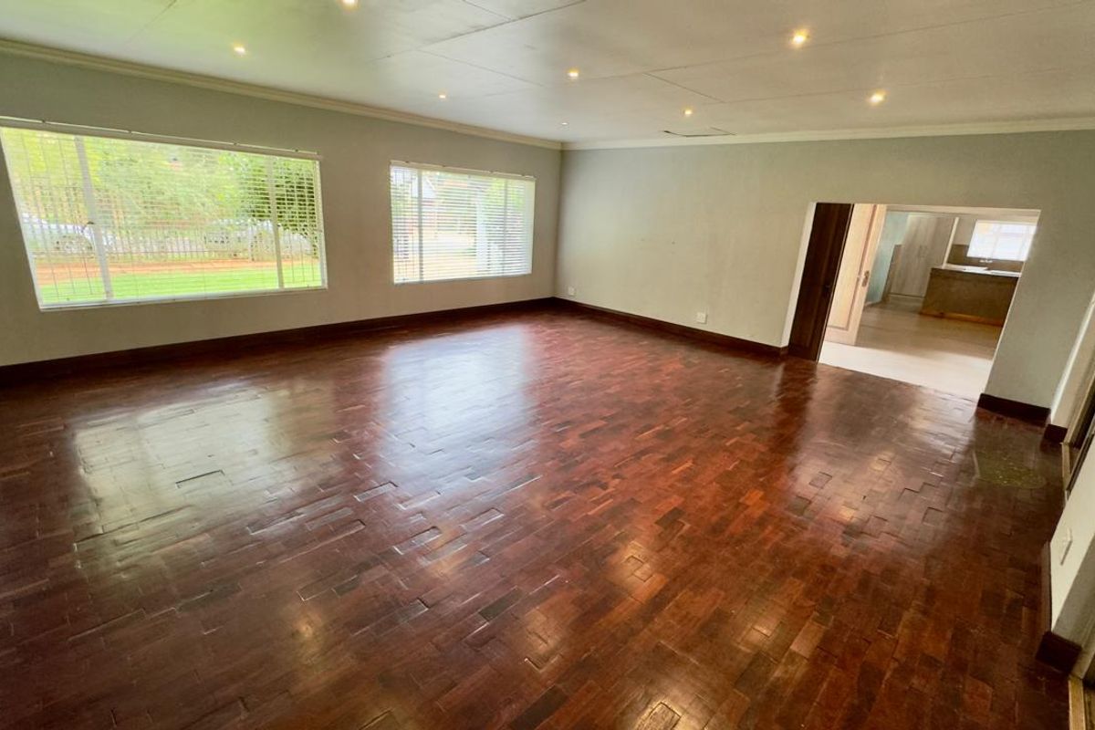 Spacious living room featuring polished parquet flooring, recessed downlighting, and large windows that provide ample natural light.