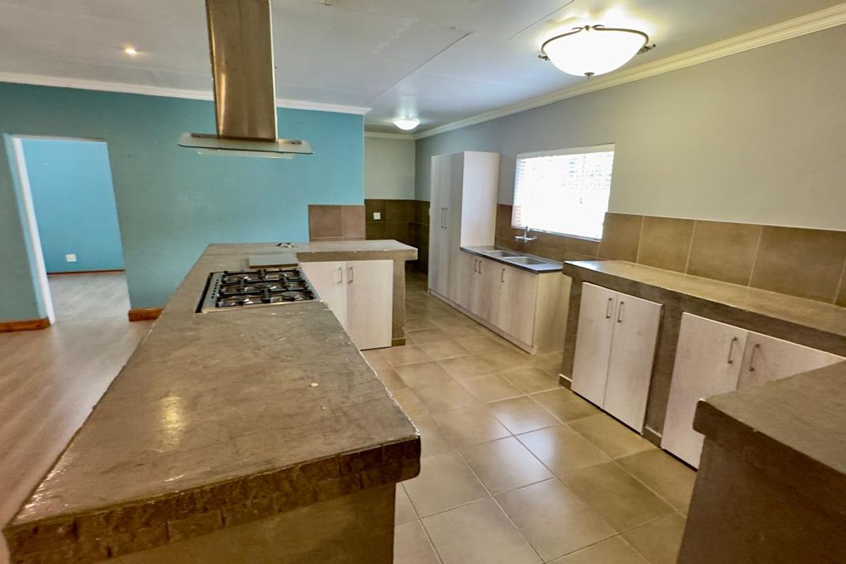 Spacious kitchen featuring concrete countertops, built-in cabinetry, a gas hob with extractor fan, and tiled flooring throughout.