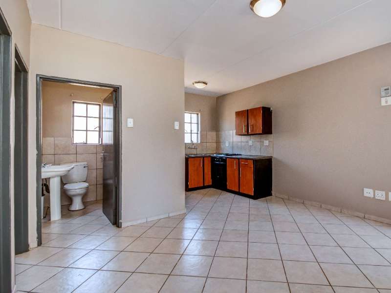 Open plan living area featuring a compact kitchen with built-in cabinetry and an adjacent bathroom with a pedestal basin and toilet.