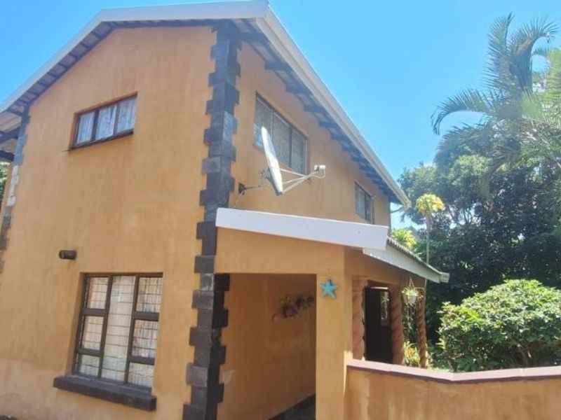 A two-story residential property featuring a textured exterior finish, tiled roof, and established garden surroundings.