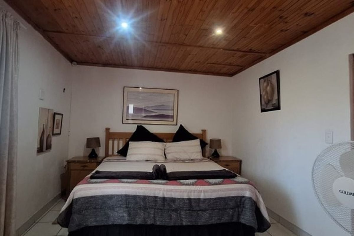 A bedroom featuring a timber-clad ceiling, tiled flooring, and recessed lighting, providing a functional and comfortable sleeping space.