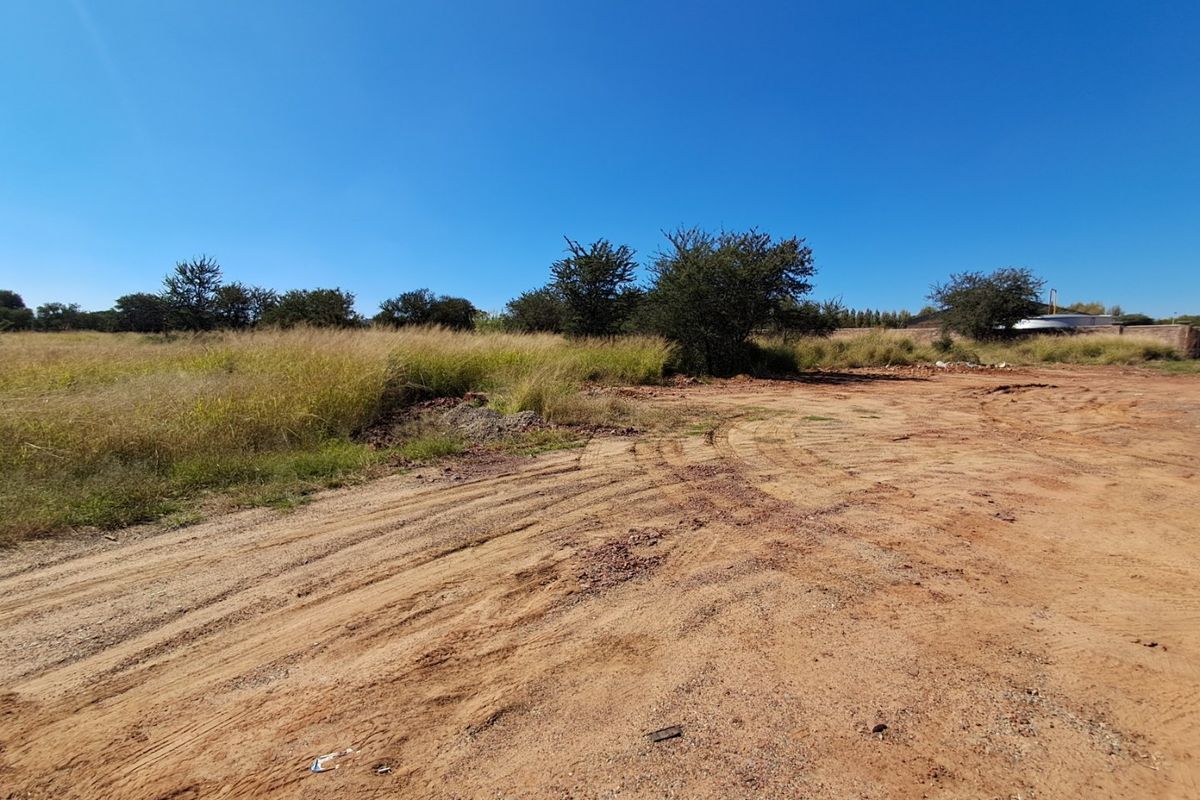 A view of a vacant residential plot featuring natural vegetation and unpaved ground, suitable for future development.