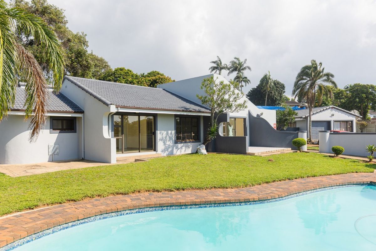 Rear view of the property featuring a well-maintained swimming pool with brick coping, a landscaped garden, and modern sliding glass doors leading to the interior.