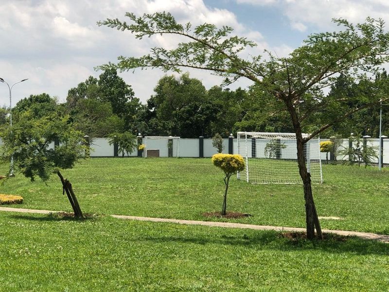 A well-maintained communal sports field featuring a grass lawn, soccer goal posts, and a secure perimeter wall.